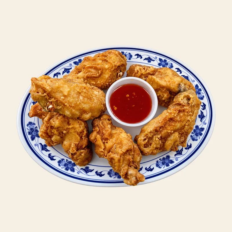 Six fried chicken wings with sweet chili sauce on a blue and white plate